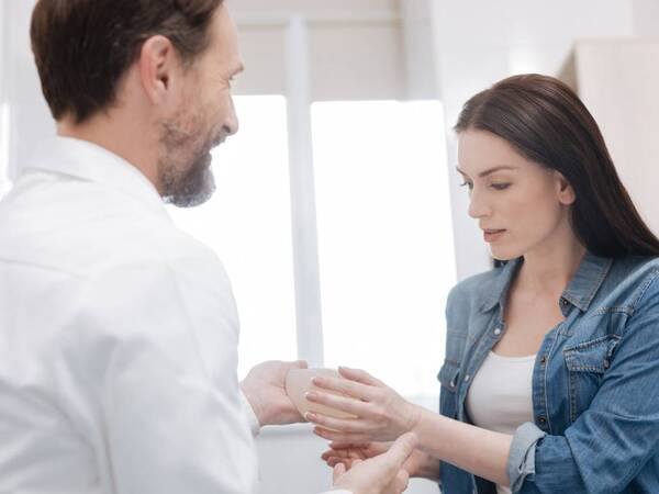 A woman feels a silicone implant before breast augmentation surgery.