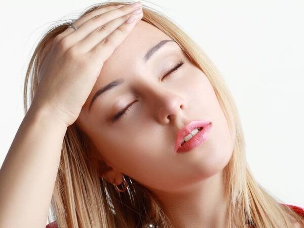 A young woman grabs her head to relief symptoms of a hangover.