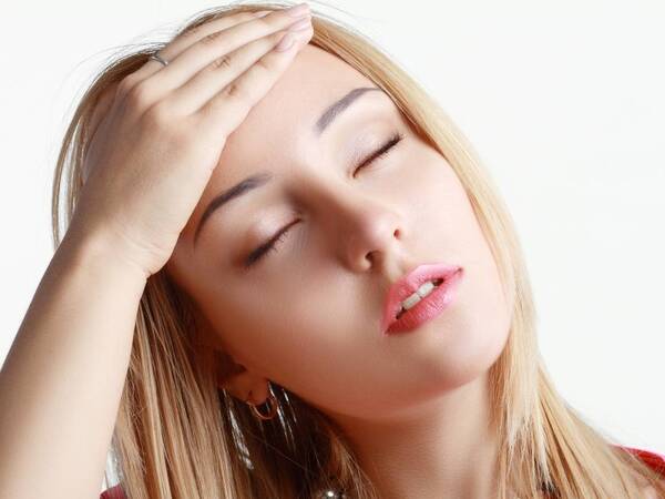 A young woman grabs her head to relief symptoms of a hangover.