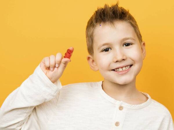 Boy smiling holding gummy vitamin.