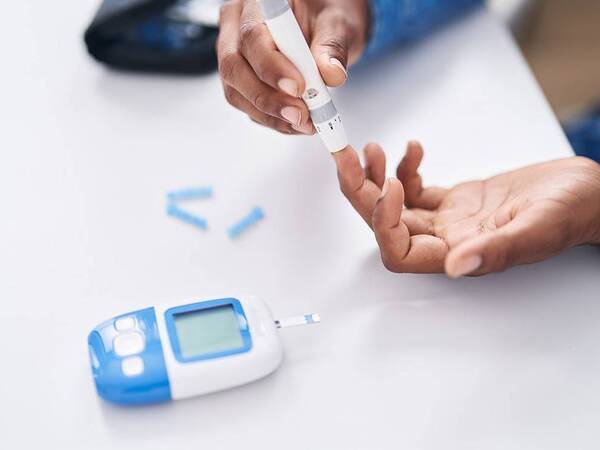 Photo shows a patient checking their blood sugar level; patient is a diabetes patient and is also dealing with mental health aspects of living with the disease.