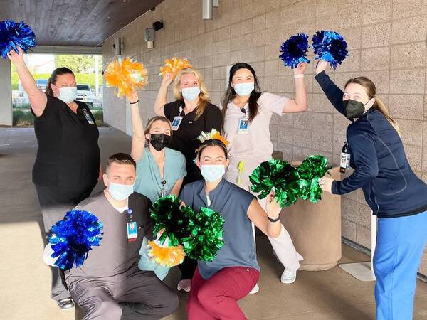 Scripps Health employees celebrate with orange and blue pom-poms.