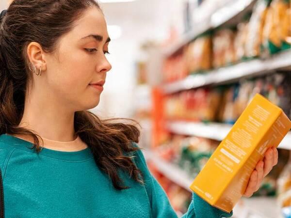 A woman stops to read the food label when shopping in the grocery store.