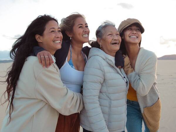 Three generations of women smile as they walk through a desert landscape.