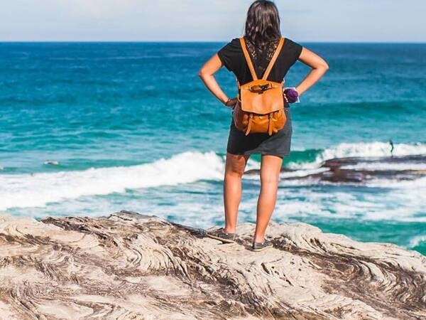 A woman stands on an ocean bluff looking out over the water. 