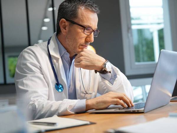 A physician uses an AI tool on the computer to help in drafting patient messages.