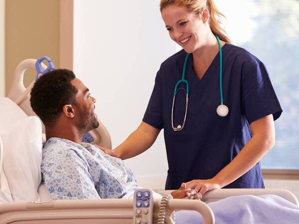 A provider checks on a patient in a hospital room.