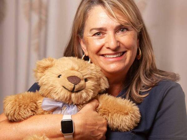 A woman hugs a therapy teddy bear comfort cub, which helps adults ease loss of loved ones.
