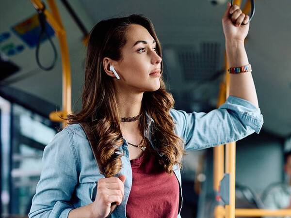 A young woman holds a handle to not lose balance while standing on a bus.