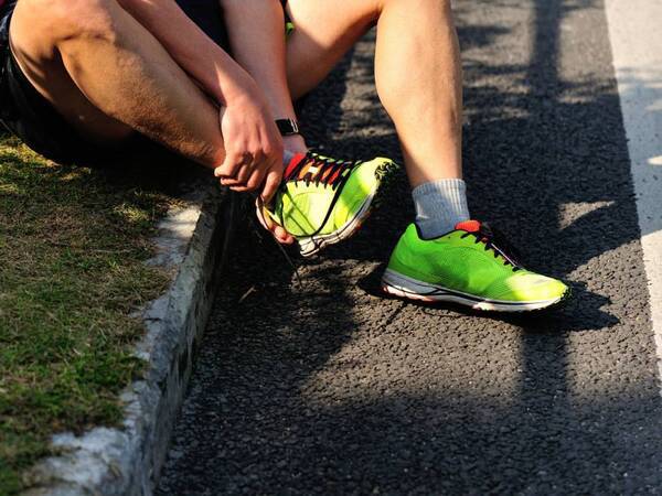 Man sits on sidewalk after turning his ankle running. Could it be a sprain or a strain or a fracture?