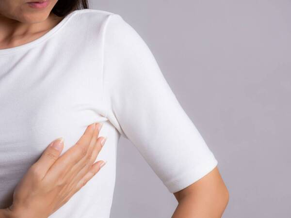 A woman performs a breast self exam. She may have dense breast density.