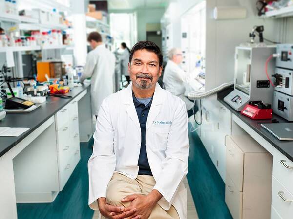 Dr. D'Lima is sitting in the lab surrounded by testing supplies, illustrating Orthopedic research performed at Scripps Health.