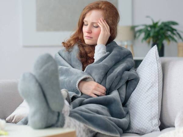 A tired looking woman with norovirus symptoms sits at home.