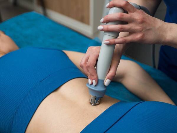 A woman receives shockwave therapy on her lower back to relieve musculoskeletal pain.