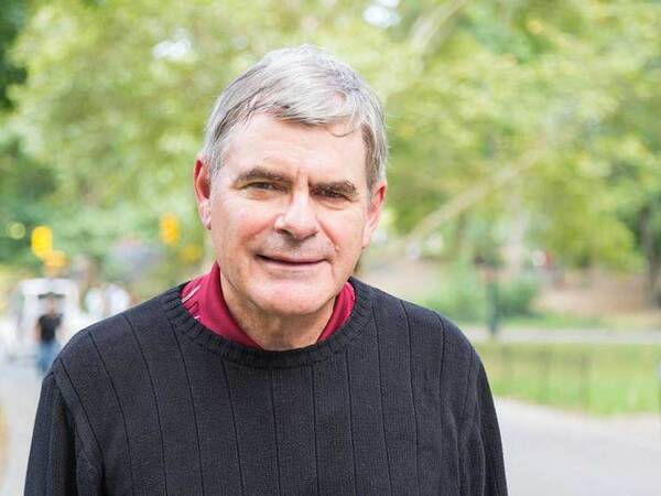 Mature man standing outside near a park.