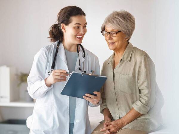 A mature female cancer patient consulting with a female doctor, illustrating the discussion of cancer treatment options.