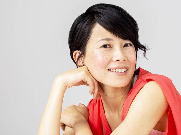 A smiling middle-aged woman with a glowing complexion represents a restored, youthful appearance after skin rejuvenation by a plastic surgeon.