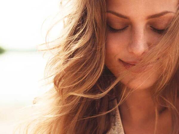 A smiling woman protects her skin by visiting the beach in the early evening.