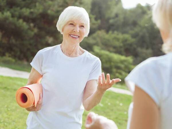 A woman holds her yoga mat as she prepares to engage in a heart healthy exercise.