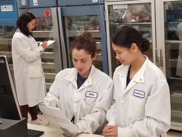 Two Scripps lab scientists in white coats review notes together.