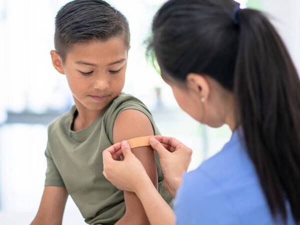A young boy in a doctor's office is receiving a flu shot, illustrating the importance of getting a flu vaccination.