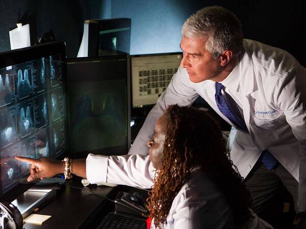 Two Scripps Clinic radiologists review imaging results on a computer monitor, representing our combination of expertise and state-of-the-art equipment.