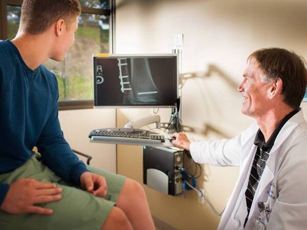 An Orthopedic Surgeon and his patient looking over some images pertaining to the young patient's ailments.