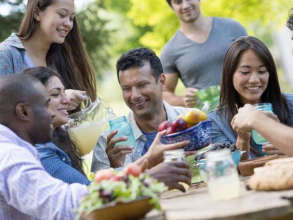 A family that is having fun and eating together at a picnic.