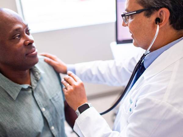 Dr. Imran Ahmed, Family Medicine physician for Scripps Coastal Medical Center speaking with a male patient.