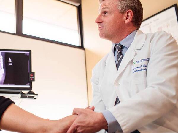 Dr. Cameron Barr, an orthopedic surgeon, examining a patient's foot and ankle during an appointment, illustrating the trusted foot and ankle care provided by Scripps Health.