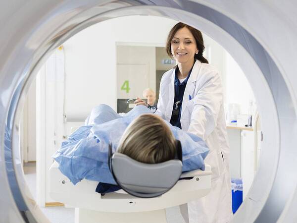 A radiologic technologist prepares a woman for a CT scan, representing a common type of imaging at Scripps Health.