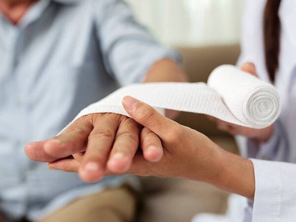 A wound therapy specialist provides treatment to a patient with a hand injury.