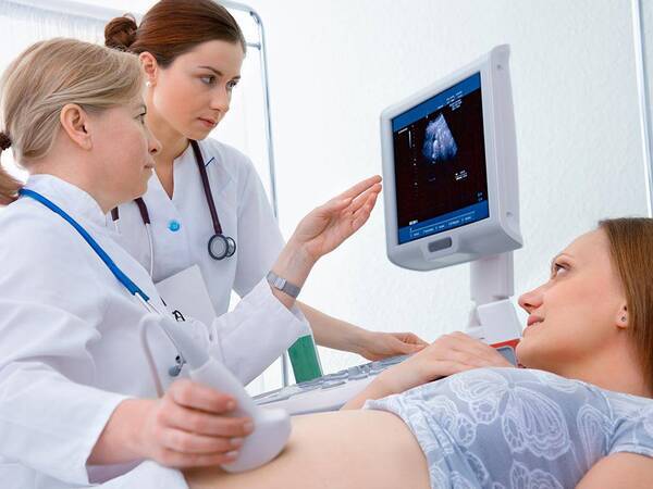 Two ultrasound experts perform a sonogram on a pregnant woman, representing one type of ultrasound performed at Scripps.
