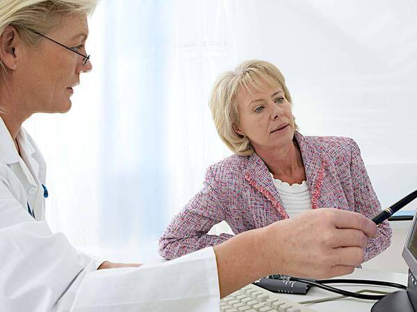 A doctor points to a computer screen while talking with her patient, representing the high-tech approach to neurointerventional surgery at Scripps.