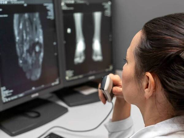 An imaging technician evaluates digital X-rays on a computer.