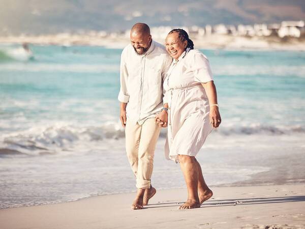 A mature couple walks down the beach, representing the successful management of kidney disease by Scripps nephrologists.