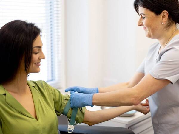 A phlebotomist prepares a woman's arm to have a blood test.
