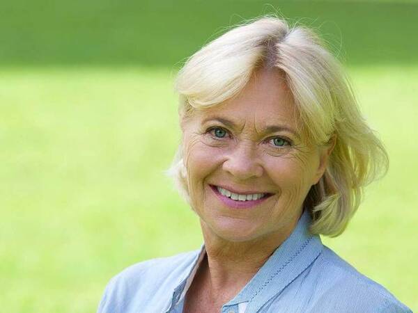 A smiling mature woman in a park represents the full life that can be led after vaginal cancer treatment.﻿