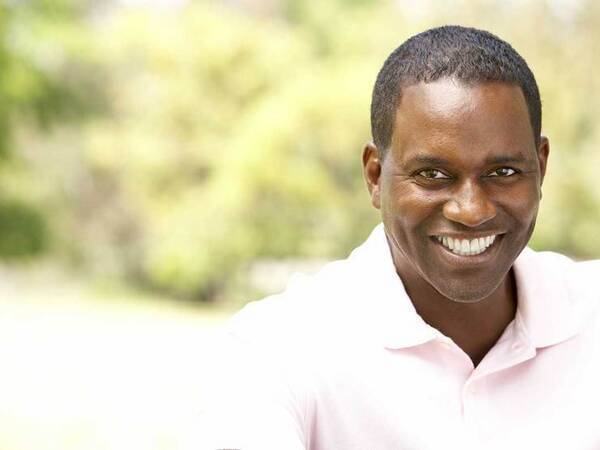 A smiling African-American man represents the full life that can be led after mouth cancer treatment.