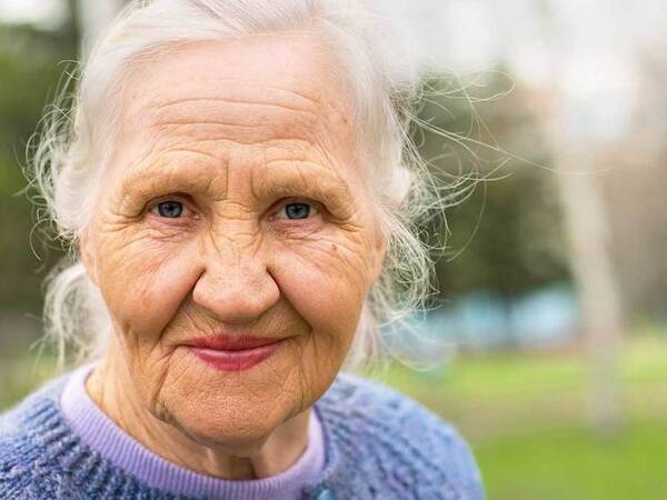 A smiling mature woman represents the full life that can be led after metastatic squamous neck cancer treatment.