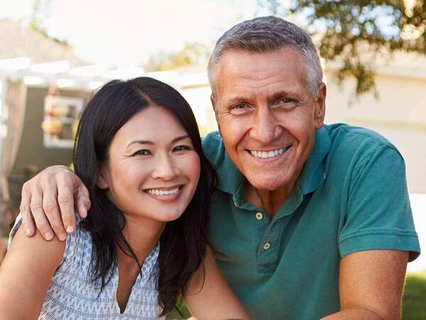 A smiling middle-aged Caucasian man and Asian woman represent the full life that can be led after treatment for sarcoma or bone cancer.