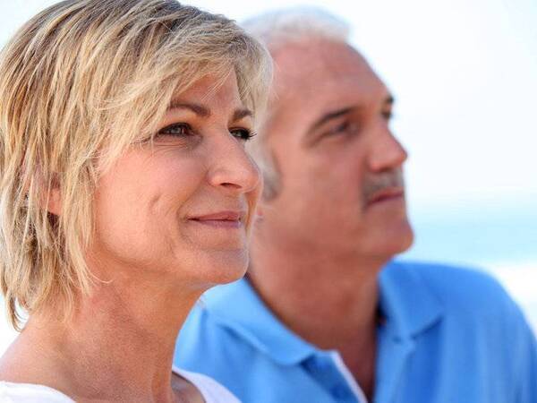 A smiling middle-aged couple on the beach represent the full life that can be led after skin cancer treatment.