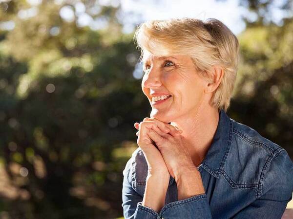 A smiling middle-aged woman represents the full life that can be led after thyroid cancer treatment.