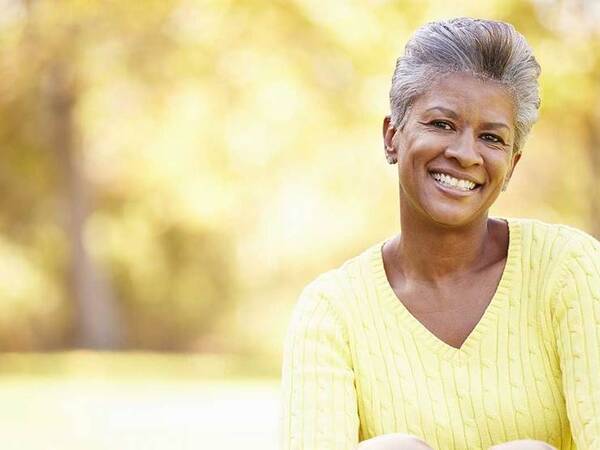 A smiling African-American woman represents the full life that can be led after gastrointestinal carcinoid tumor treatment.