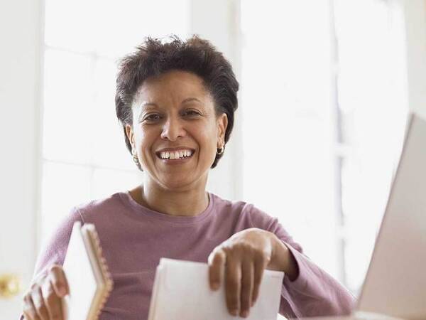 A smiling middle-aged African-American woman represents the full life that can be led after uterine sarcoma treatment.