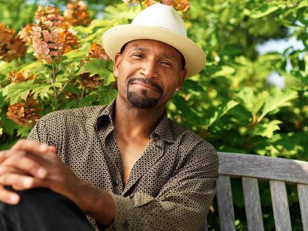 A smiling middle-aged African-American man on a park bench represents the full life that can be led after kidney cancer treatment.