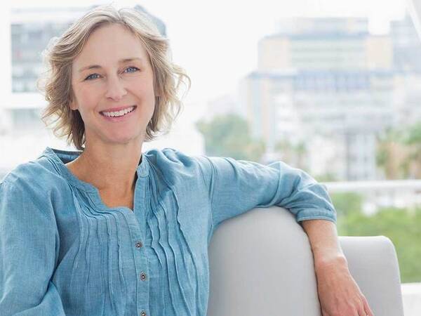 A smiling middle-aged woman represents the full life that can be led after adrenal cancer treatment.