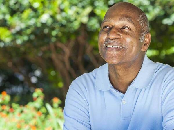 A smiling African-American man represents the full life that can be led after laryngeal or hypopharyngeal cancer treatment.