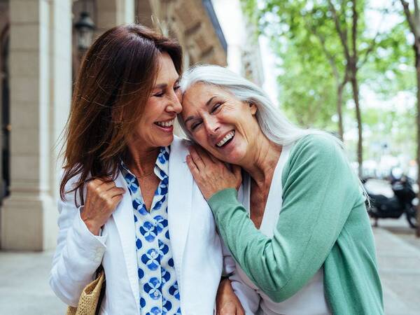 Two middle-aged woman laugh on a city street, representing a fuller life with treatment for renovascular disease.