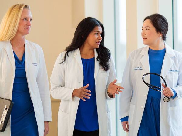 Three female cardiologists walking and discussing women's heart care issues and topics.